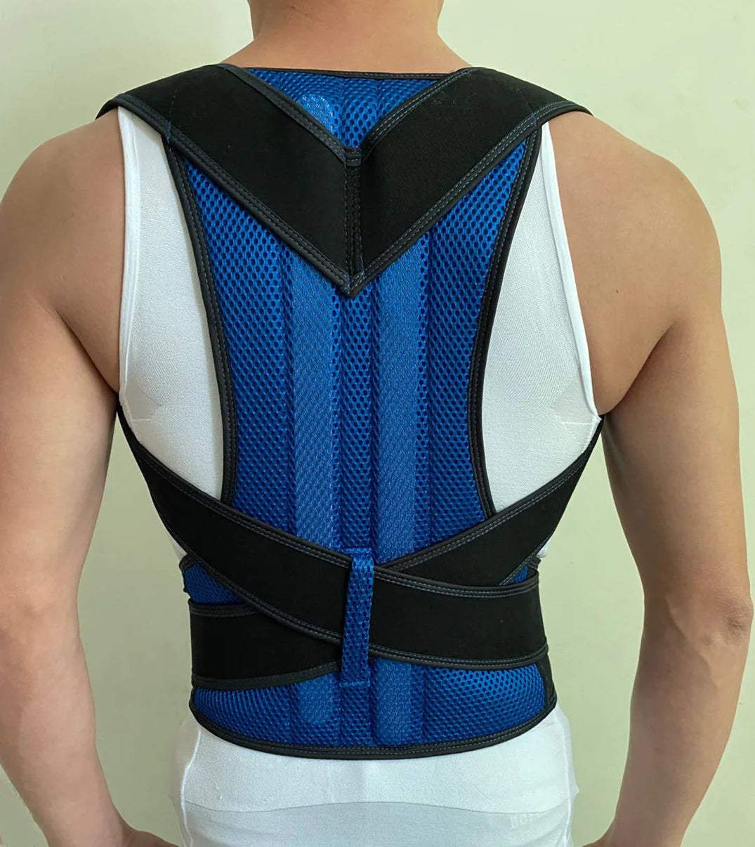 Person wearing a blue and black posture corrector against a plain background