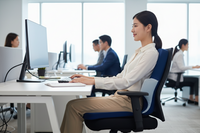 Woman sitting at a desk in an office with colleagues in the background