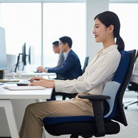 Woman sitting at a desk in an office with colleagues in the background